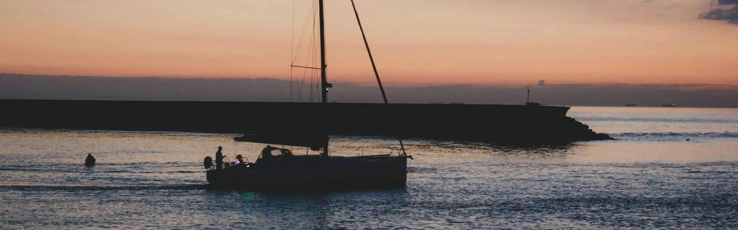 Voilier rentrant au port au coucher du soleil