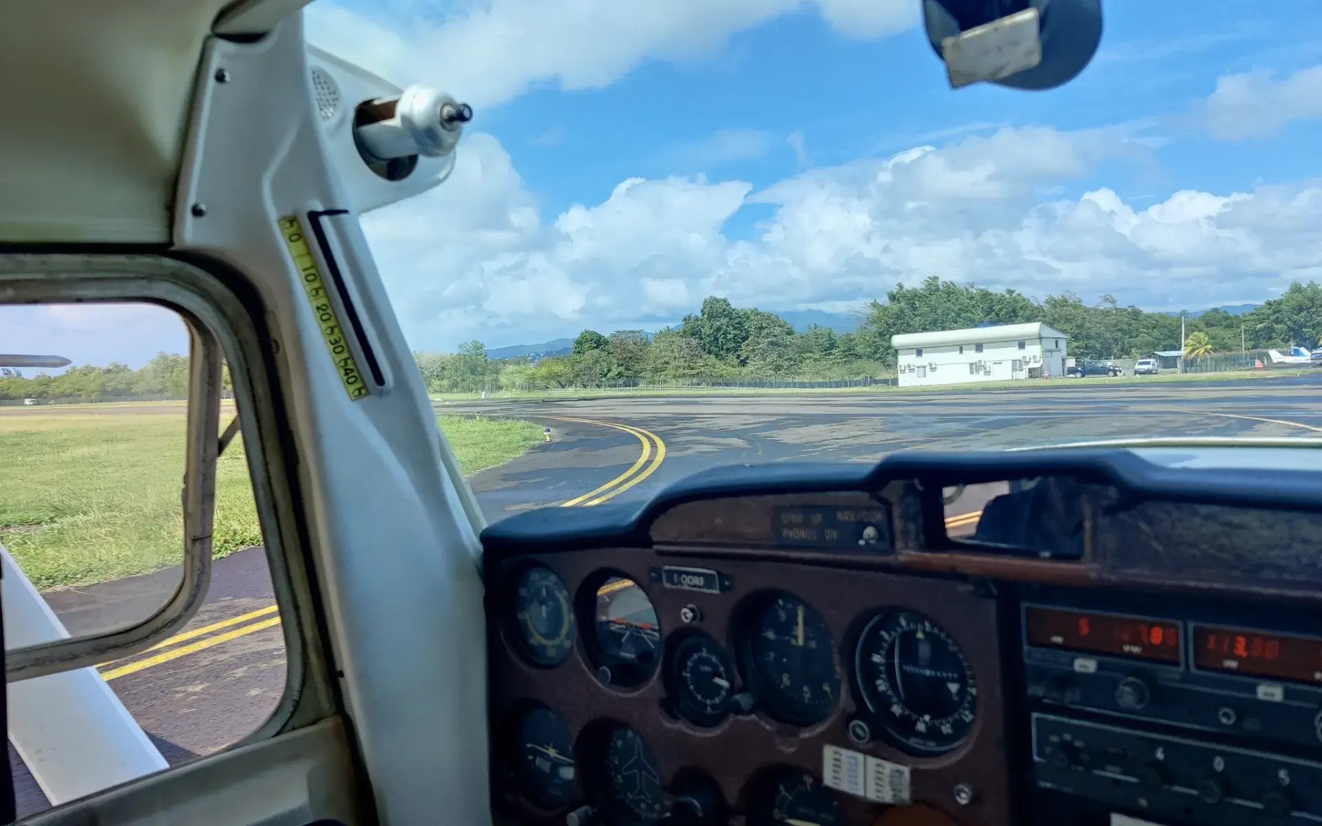 Tableau de bord d'un avion léger au sol, piste et bâtiment de l'aérodrome par le pare-brise