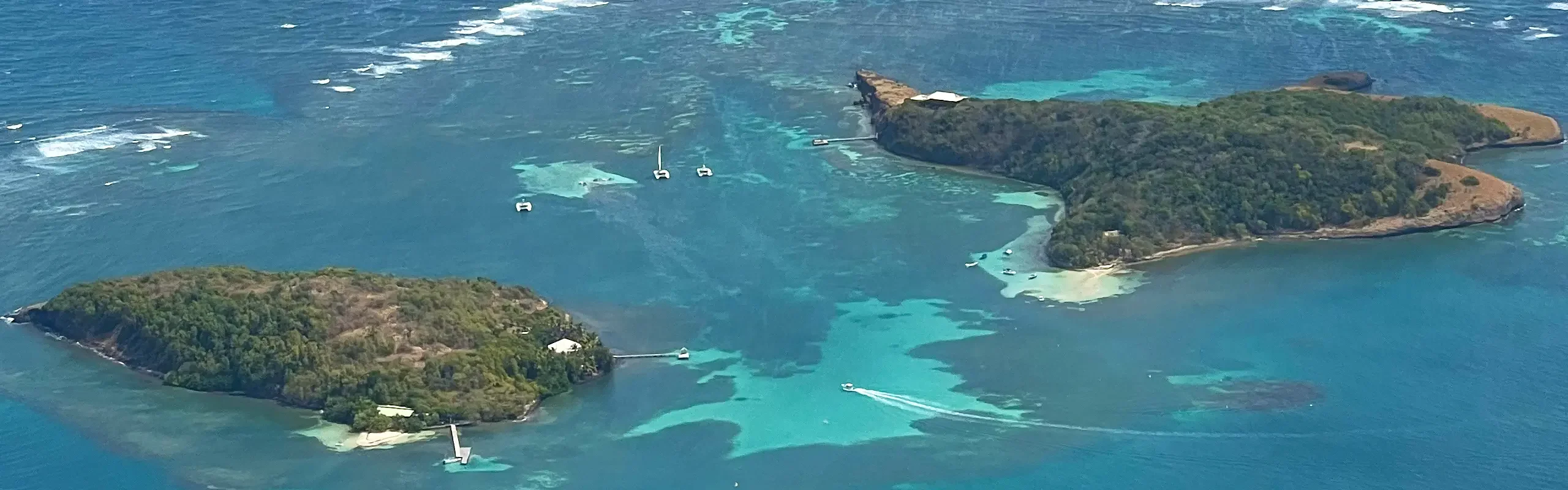 Les îlets Oscar et Thierry vus du ciel, leurs pontons et les hauts-fonds de sable clair où mouillent les catamarans